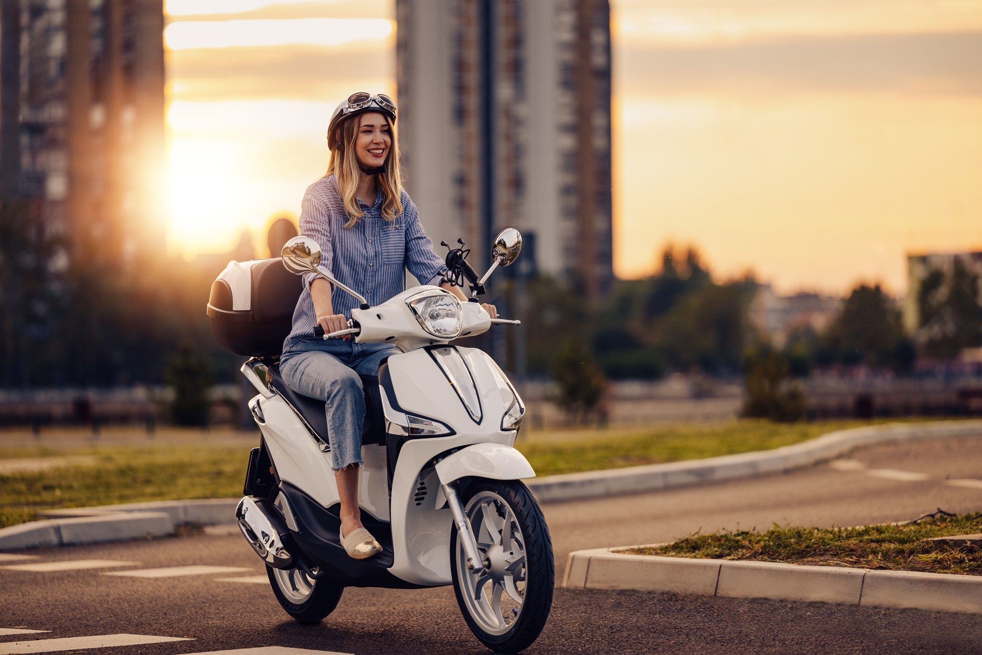 Cheerful young woman driving scooter in the city